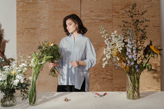 一位女士将美丽的花朵插在花瓶里，在室内展示出缤纷的色彩