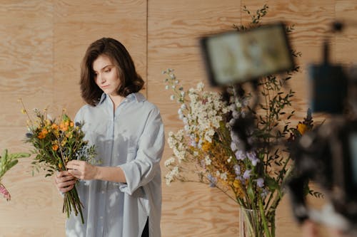 Woman in White Long Sleeve Dress Holding Bouquet of Flowers