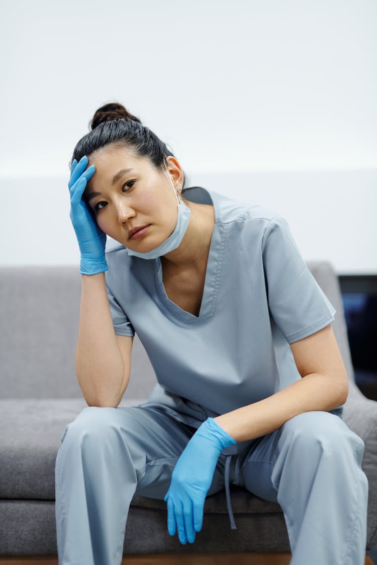 A Woman In Scrub Suit Holding Her Head