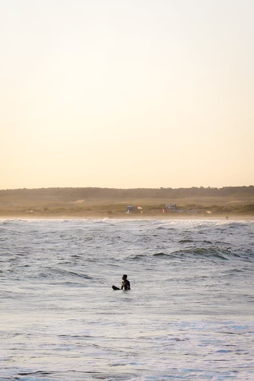 Free Anonymous surfer riding waves in sea during sundown Stock Photo