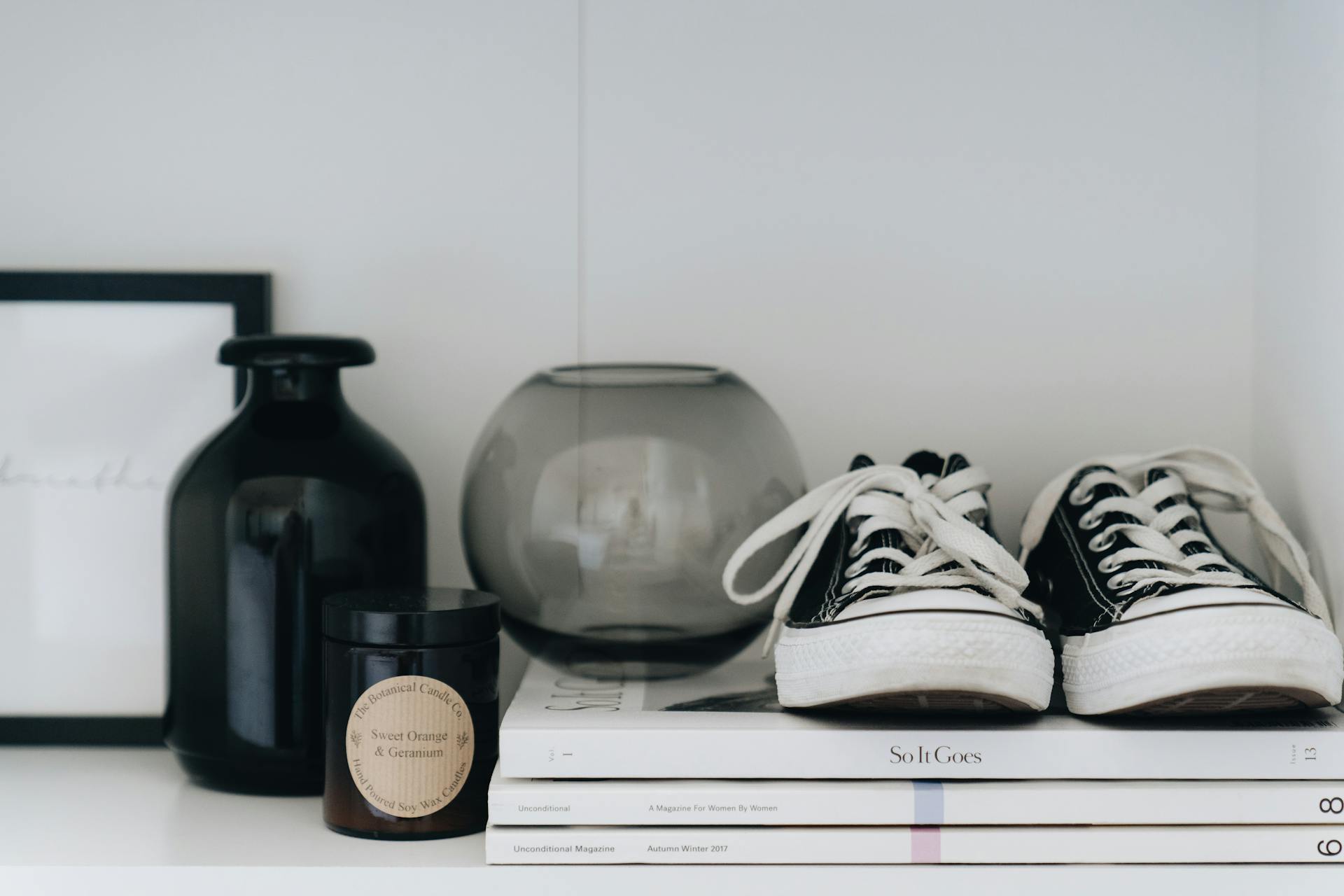 Black and white sneakers on a shelf with decorative items for a minimalist aesthetic.