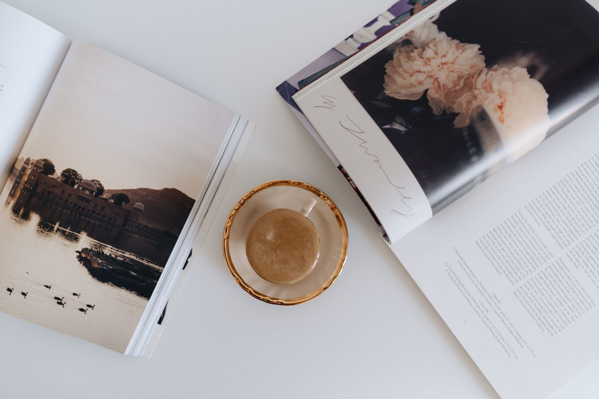 Open lifestyle magazines and a cup of coffee on a white surface