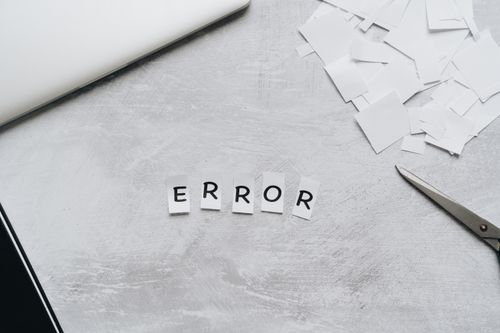 Free Creative concept showing the word 'error' with cut out letters on a table with scissors and paper. Stock Photo