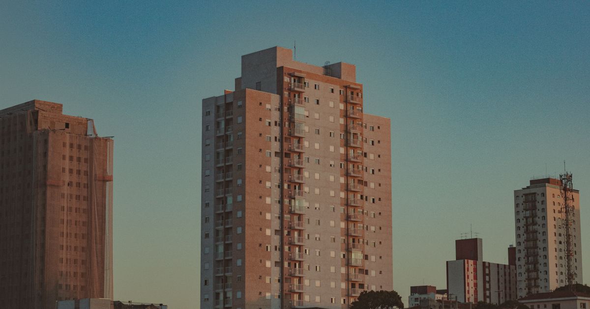 Cenário urbano capturado com edifícios altos modernos sob um sereno céu azul ao amanhecer.