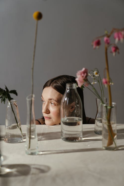 Woman in White Shirt Sitting Beside Table With Drinking Glasses