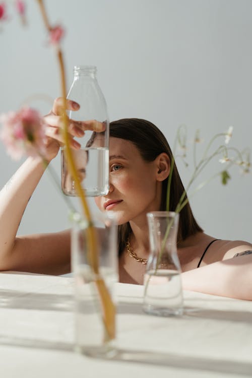 Woman in Black Brassiere Holding Clear Glass Bottle