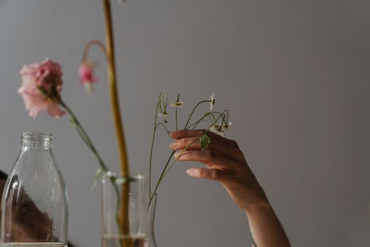 室内玻璃花瓶旁，双手拿着精致鲜花的特写