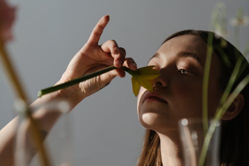 Free Woman Holding While Smelling Yellow and Green Flower Stock Photo