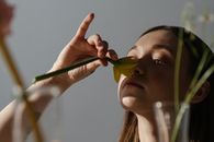 在温暖的自然光下，成年妇女轻轻闻着室内水仙花的香味