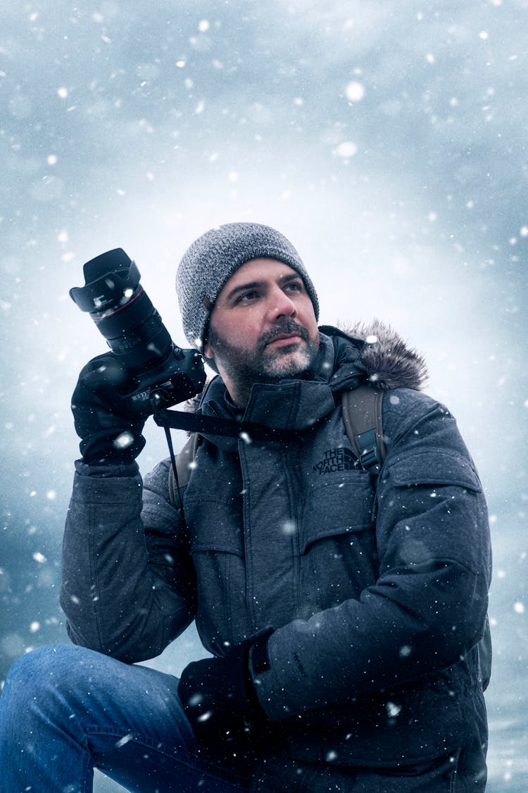 Man In Winter Jacket Holding Black Dslr Camera