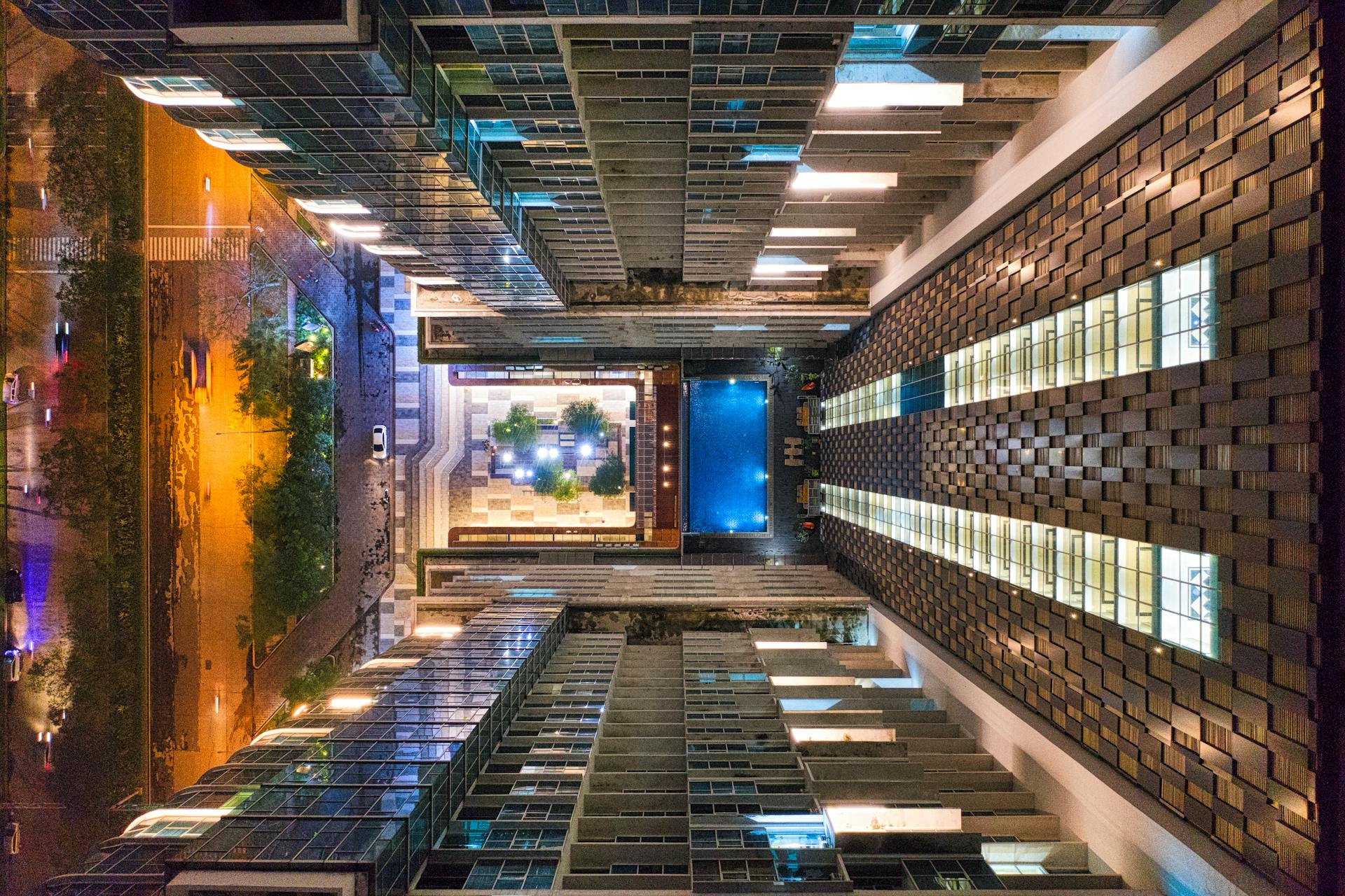 Aerial night view of a modern urban building complex with illuminated windows and geometric patterns in Banten, Indonesia.