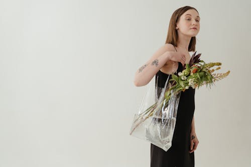 Woman in Black Sleeveless Dress Holding White Flowers