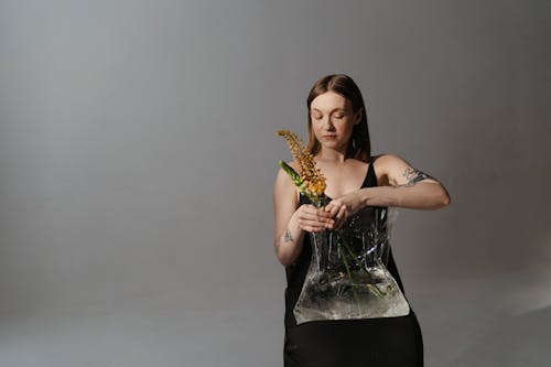 Woman in Black Tank Top Holding Yellow Flowers