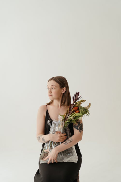 Woman in White Sleeveless Dress Holding Bouquet of Flowers