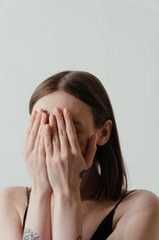 一个女人用手捂住脸，流露出害羞与匿名的感觉
