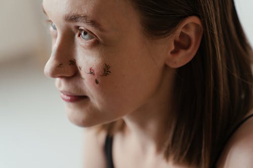 Close-Up Photo of Woman With Floral Art Tattoo on Her Face