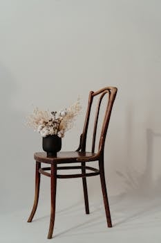 Minimalist still life featuring a dried flower arrangement on a vintage wooden chair.
