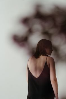 从后面看，一位穿着黑色连衣裙的女子带有柔和的花卉模糊