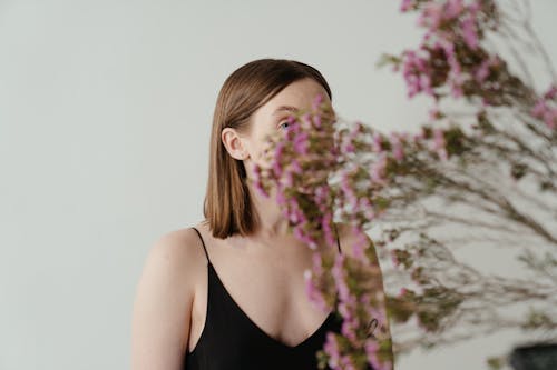 Woman in Black Tank Top Standing Near White Wall