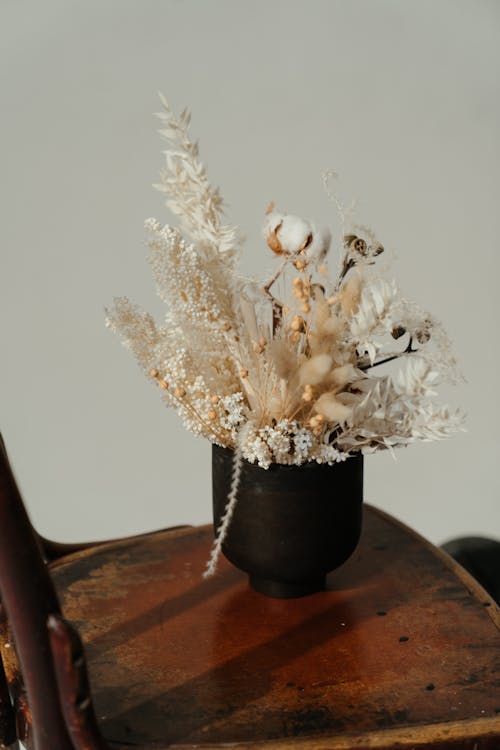 White Flowers in Black Ceramic Vase on Brown Wooden Table