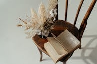 一束干花和一本打开的书放在木椅上，营造出乡村的静物场景