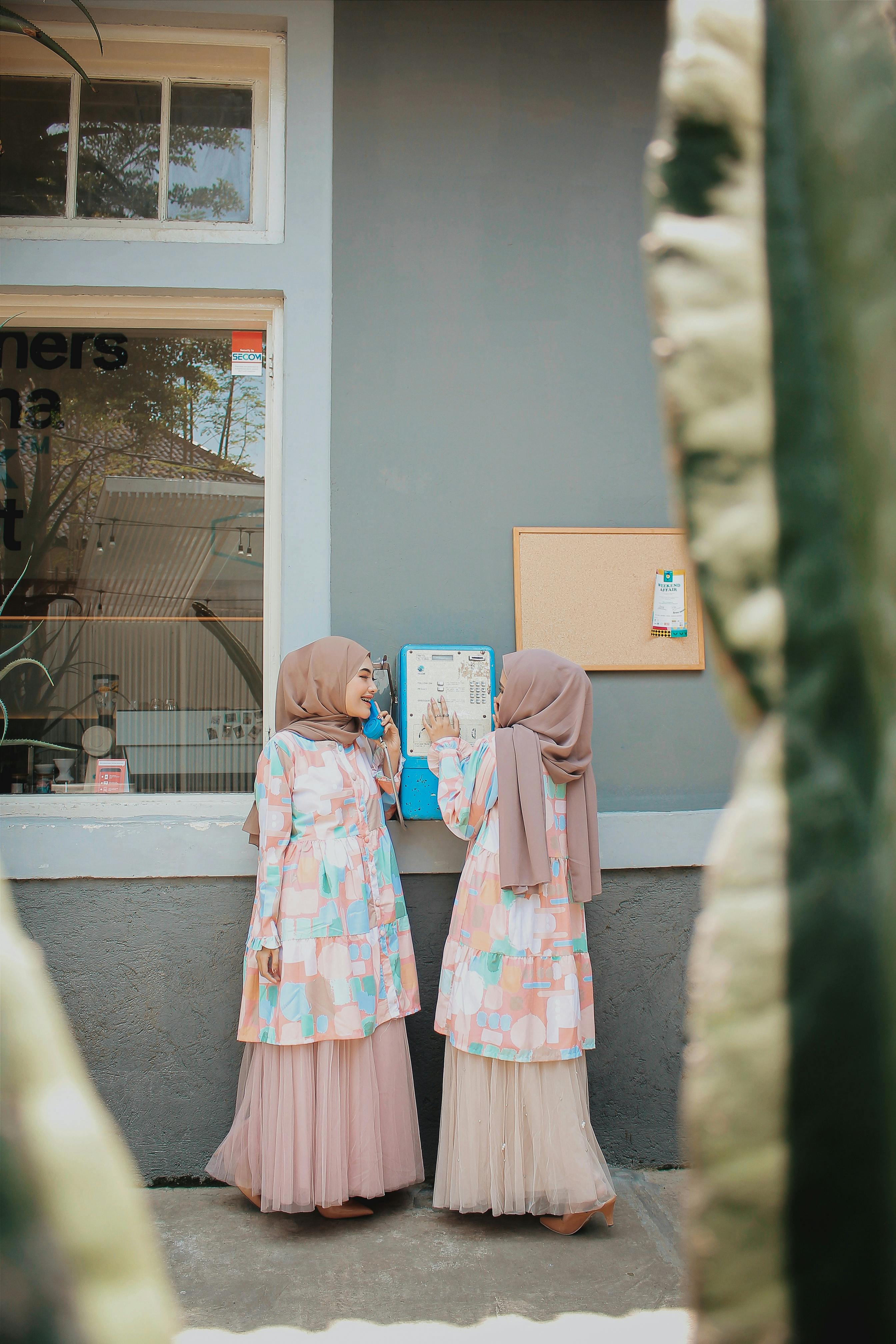 women in islamic clothes using street payphone