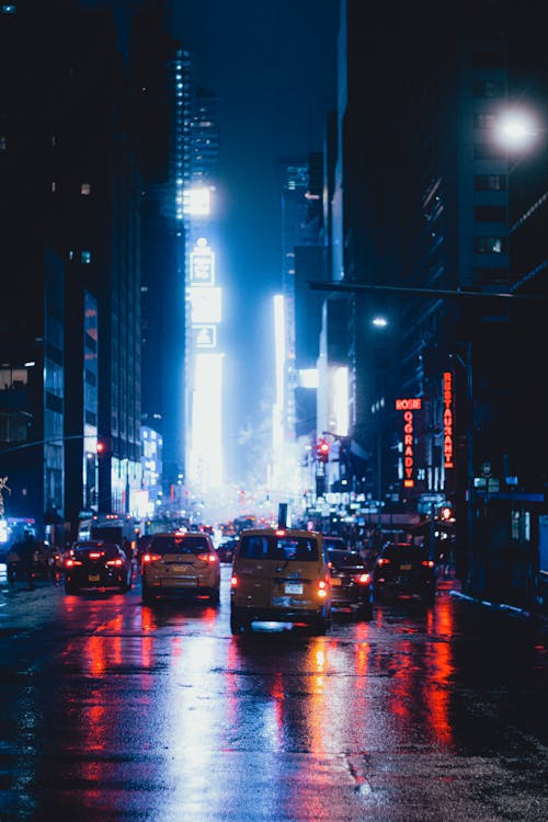 Modern city street with cars driving along asphalt road during dark night