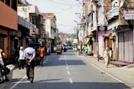 Citizens walking along street with shabby buildings and tuc tuc bikes parked on roadside in poor area of Asian town on sunny weather