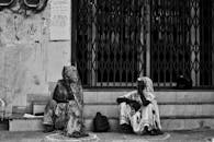 黑白图像中，两名穿着传统长袍的妇女正在城市台阶上休息