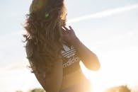 一位身穿阿迪达斯上衣的女子在户外享受日落，展现出运动风格和轻松的心情