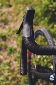 Detailed view of a bicycle handlebar in an outdoor setting, evoking motion and summer vibes.