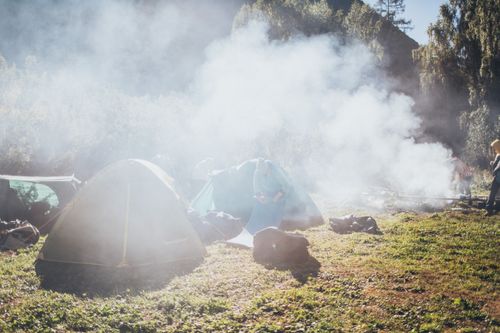 Free Serene outdoor camping scene with tents and smoke in a lush forest setting. Stock Photo