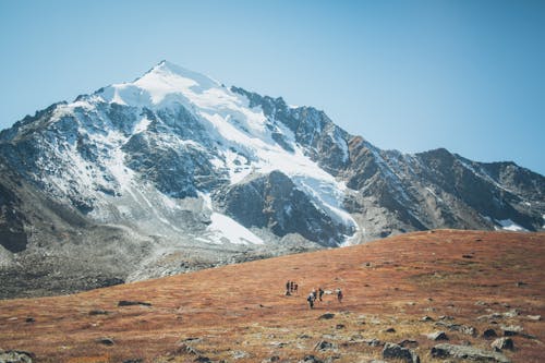 People Walking near a Snow Covered Mountain