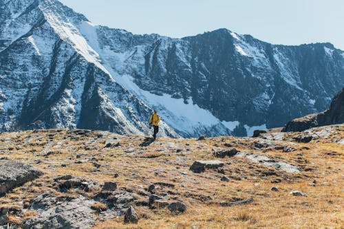 A Man Walking near the Snow Covered Mountains