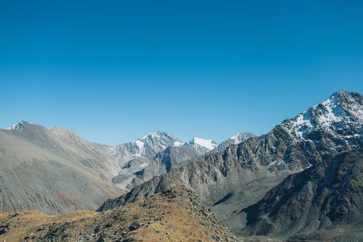 Stunning high-altitude view of rocky mountains with clear blue sky backdrop, ideal for nature lovers.
