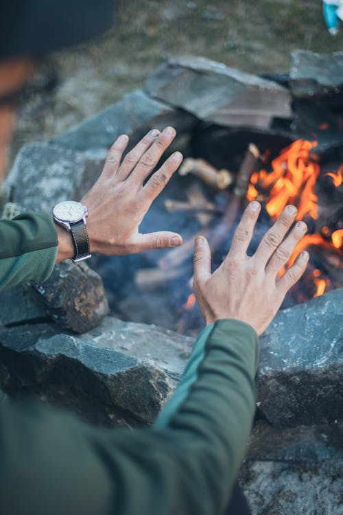 Male tourist warming hands over fire