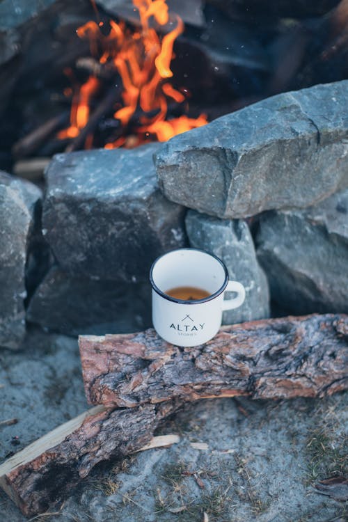 Burning fire and tea cup on log