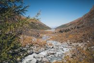 River flowing through mountainous terrain under blue sky