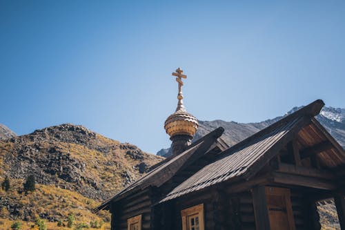 Low angle of aged wooden church located in mountainous valley against cloudless blue sky