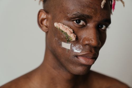 Free Unique artistic portrait of a man with a flower and band-aid on his cheek. Stock Photo