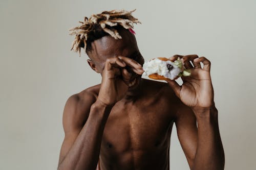 Topless Man Holding White and Brown Bread