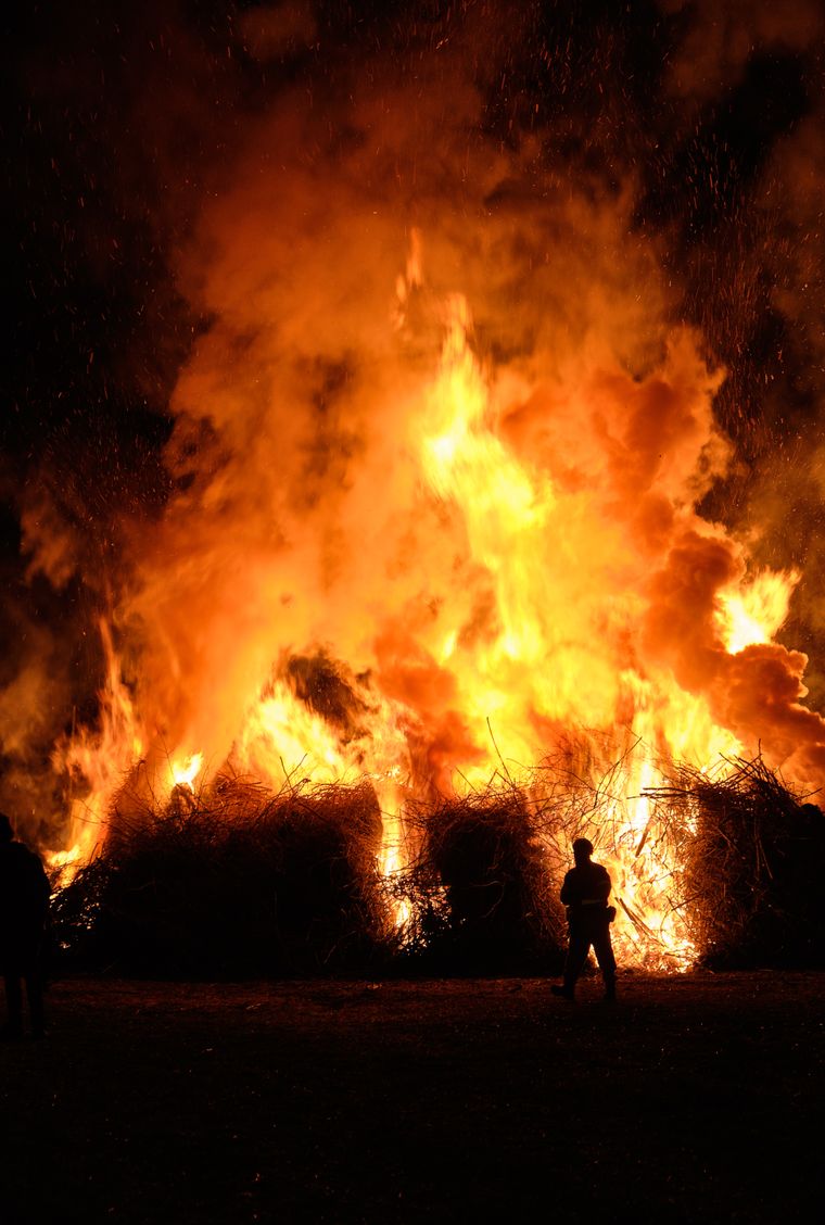 A figure silhouetted against a towering bonfire — photo by marco allasio on Pexels