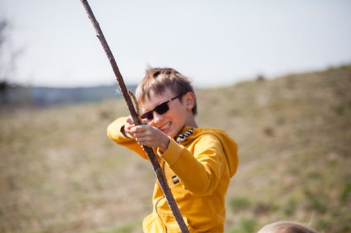 Free A happy child in sunglasses playing with a stick outdoors, capturing the essence of fun and energy. Stock Photo