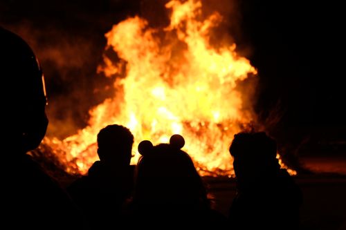 Free Silhouetted people observing a large bonfire outdoors at night in Torino, Italy. Stock Photo