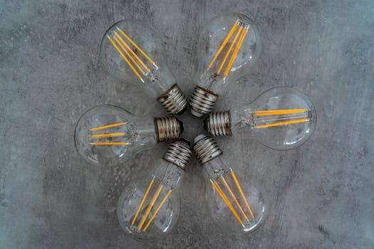 Artistic arrangement of Edison light bulbs in star pattern on concrete background.