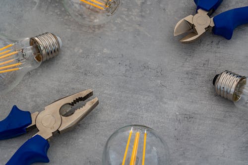 Photo of Incandescent Lightbulbs and Pliers on Gray Surface