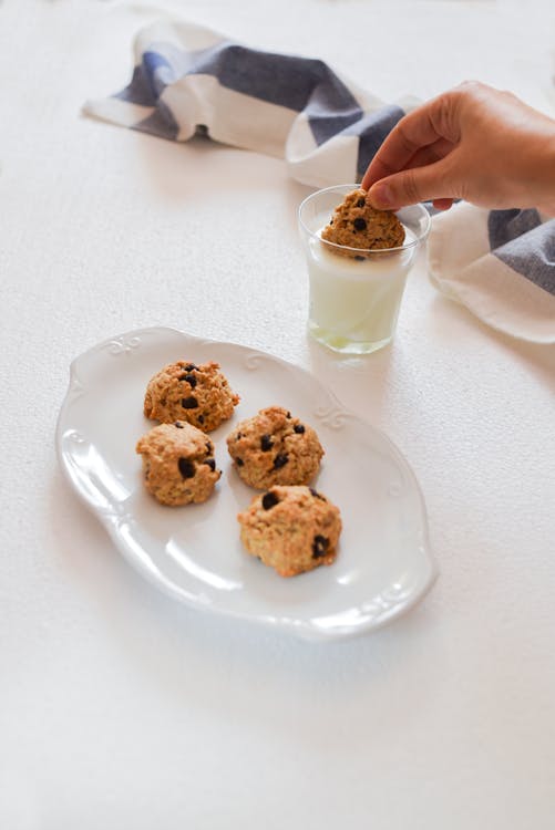 Free Photo of Person's Hand Dipping Cookie on Glass With Milk Stock Photo
