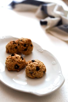 Three freshly baked chocolate chip cookies on a white plate.