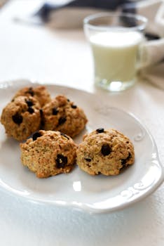 Homemade chocolate chip cookies with milk on a white plate.