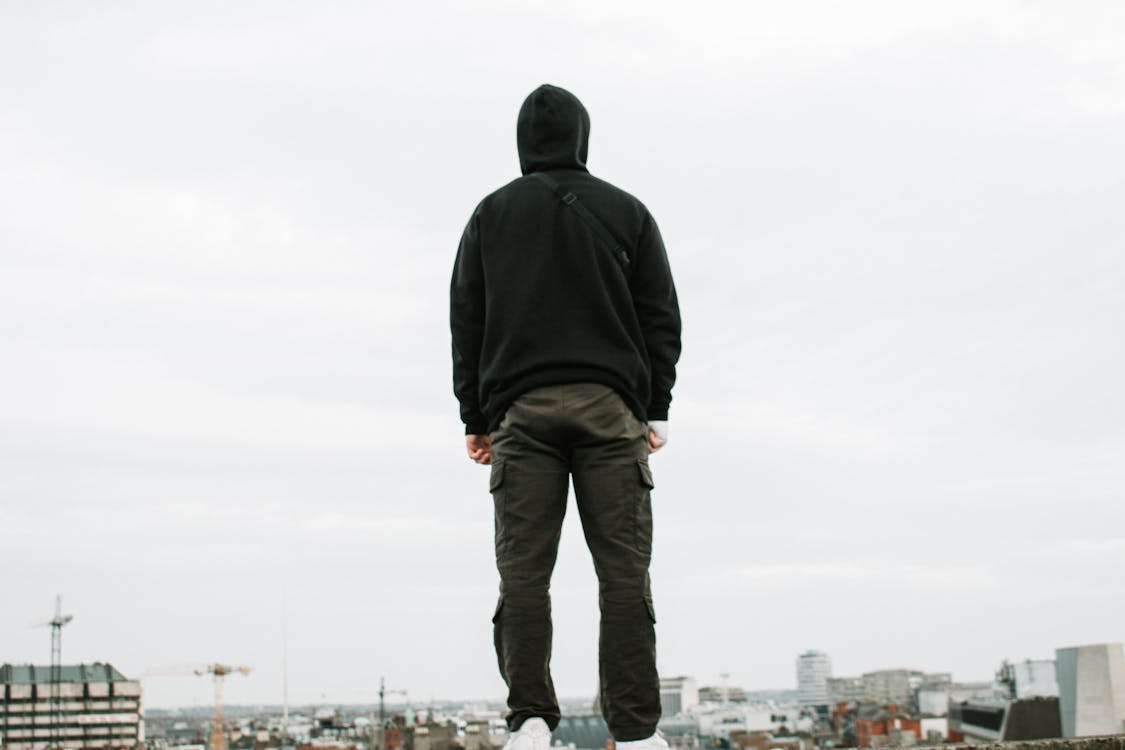 Person in Black Hoodie and Cargo Pants Standing on Top of Building